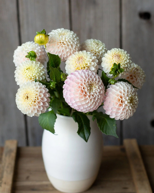 White vase with a bouquet of flowers on a wooden surface and background